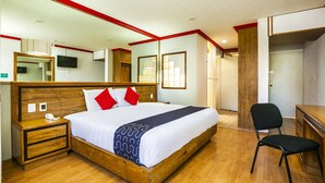 Een hotelkamer met een houten bed, een bureau, een stoel en een televisie aan de muur.
