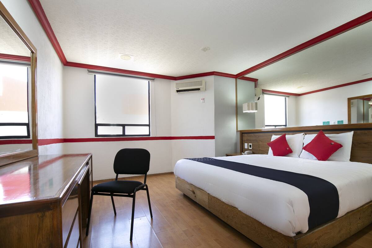 Una habitación de hotel con una cama de madera, un escritorio, una silla y una ventana.