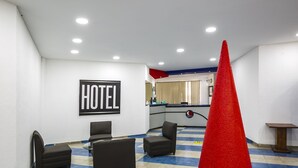 Een hotel lobby met een receptiebalie, een groot 'HOTEL'-bord en een rode kegel in het midden.