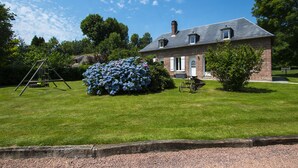 A house with a brick exterior, a thatched-roof structure in the background, and a well-maintained lawn. - THE PIRATES FARM (MANNEVILLE la raoult)