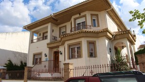 A two-story building with a balcony, a gated entrance, and a clear sky. - Villa Rural Campillo de Arenas (Campillo de Arenas)