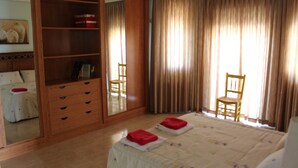 A bedroom with a bed, a wooden wardrobe, a chair, and a mirror. - Villa Rural Campillo de Arenas (Campillo de Arenas)