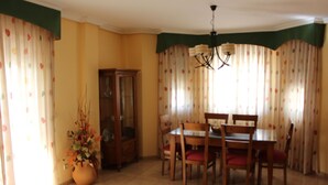 A dining area with a wooden table and chairs, a cabinet, and curtains with a polka dot pattern. - Villa Rural Campillo de Arenas (Campillo de Arenas)