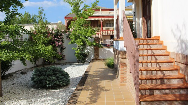 A traditional house with a tiled patio, a staircase, and a garden with trees and shrubs. - Villa Rural Campillo de Arenas (Campillo de Arenas)