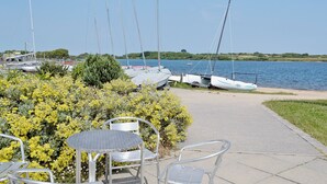A marina with sailboats docked, a paved walkway, and a table with chairs in the foreground. - 2 bedroom accommodation in Mount Hawke, near Redruth (Mount Hawke, near Redruth)
