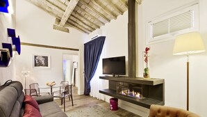 A modern living room with a sofa, a television, a fireplace, and a dining area. - Timeless Beauty Downtown (Firenze)