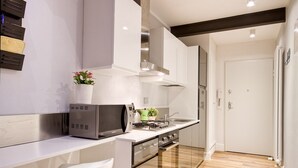A modern kitchen with a built-in microwave, stove, and sink. There is a white chair and a potted plant on the counter. - Timeless Beauty Downtown (Firenze)