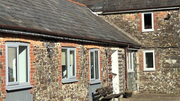 A stone building with multiple windows and a bench in front. - Linhay, character 1 bed 19th century cottage, peaceful location (Bude)