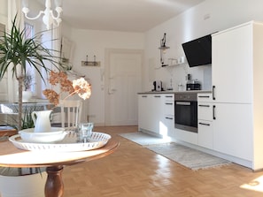 Eine moderne Küche mit weißen Schränken, einem eingebauten Backofen und einem Flachbildfernseher.