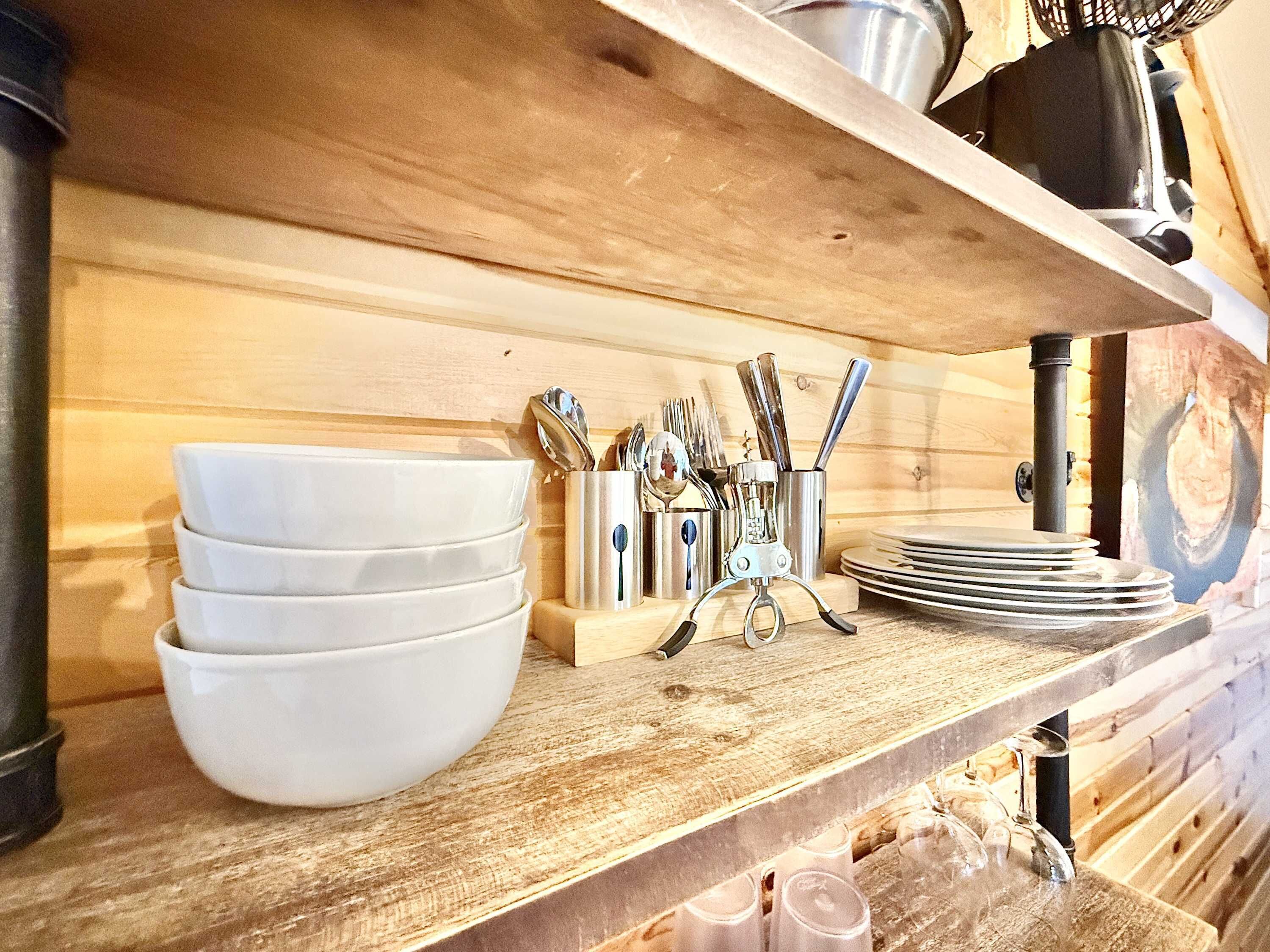 A wooden shelf with white bowls, a utensil holder, and a metal pot.