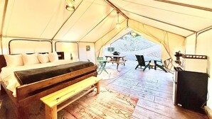 A tented accommodation with a bed, a bench, a table, chairs, and a speaker. - Glamping Tent near Zion with A/C & Private Bath (Orderville)