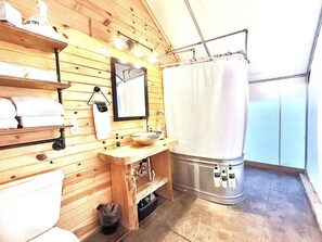 A wooden interior with a sink, mirror, towel rack, and a shower curtain.