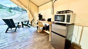 A compact kitchen with a microwave, a small refrigerator, and a table with chairs. - Glamping Tent near Zion with A/C & Private Bath (Orderville)