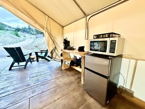A compact kitchen with a microwave, a small refrigerator, and a table with chairs. - Glamping Tent Near Zion w/ AC & Private Bathroom (Orderville)