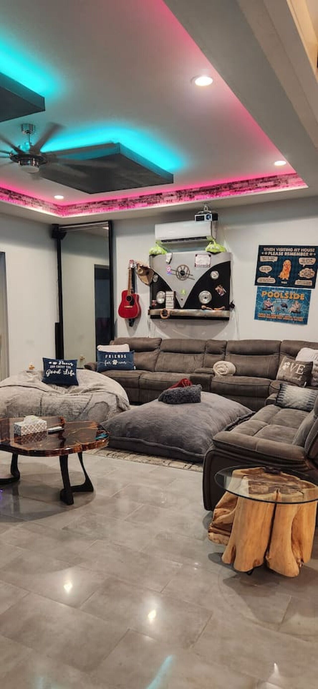 A modern living room with a sectional sofa, a coffee table, a guitar, and a poster on the wall.