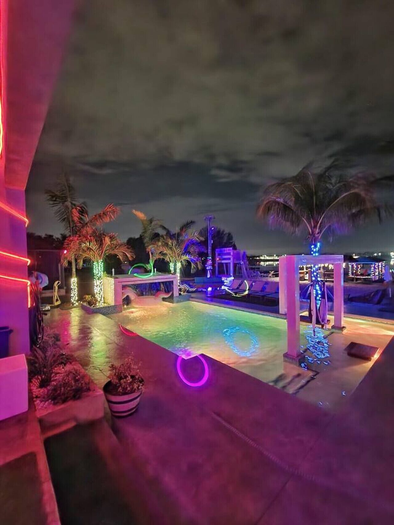 A nighttime pool area with illuminated structures and palm trees.