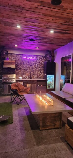 Una cocina moderna con pared de piedra, un letrero de neón y una parrilla empotrada.