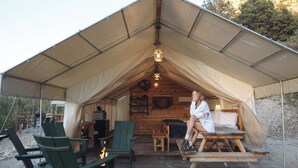 A tented accommodation with a dining table, chairs, and a fireplace.