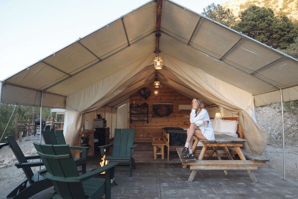 A tented accommodation with a dining table, chairs, and a fireplace.