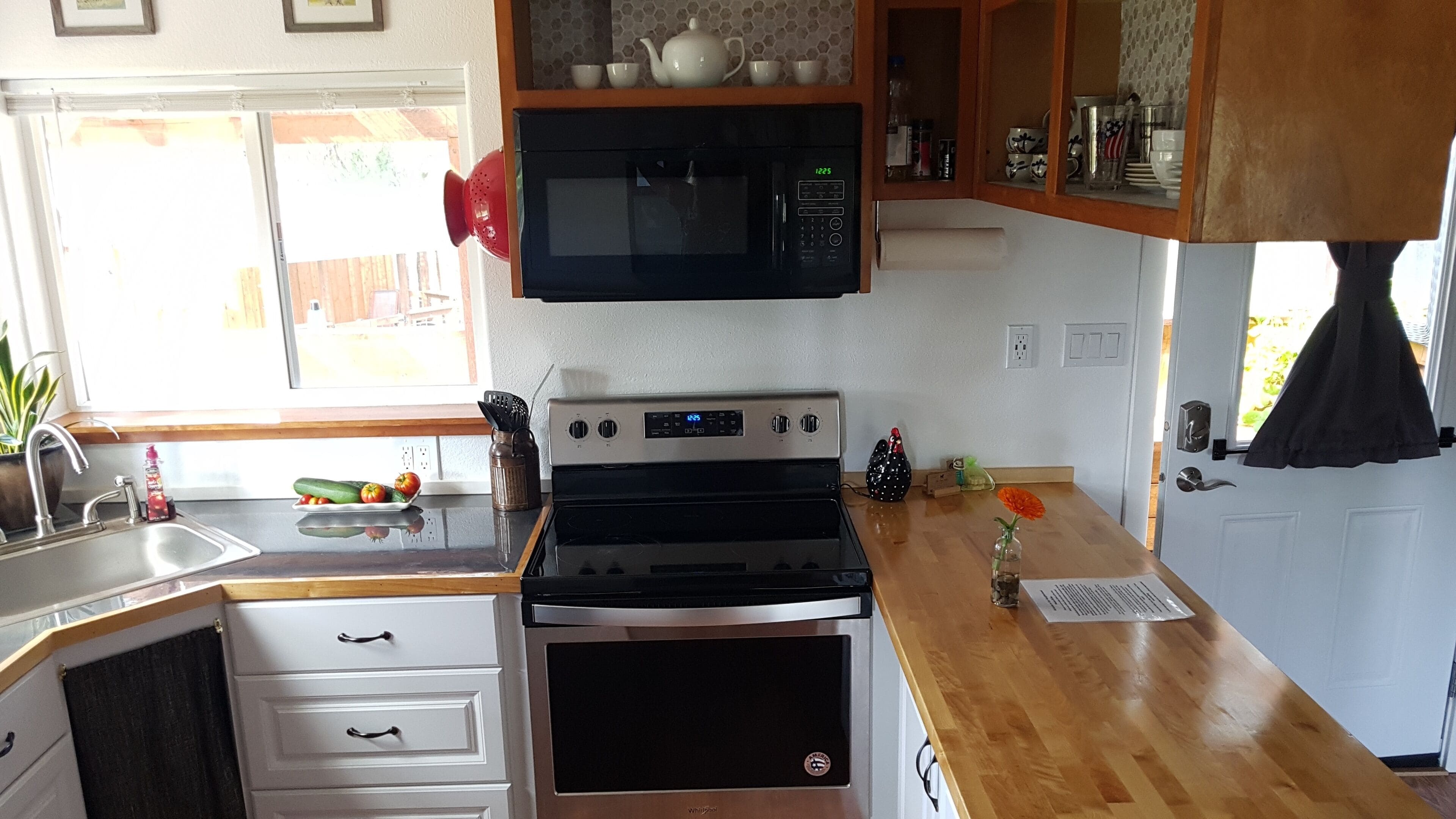A kitchen with a microwave, stove, sink, and wooden cabinets.