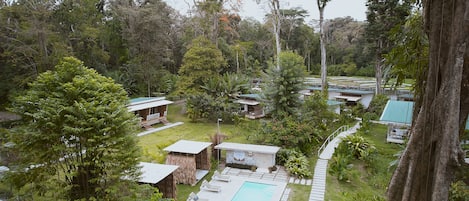 Un resort con múltiples alojamientos tipo cabaña rodeado de exuberante vegetación, una piscina y un jardín bien cuidado.