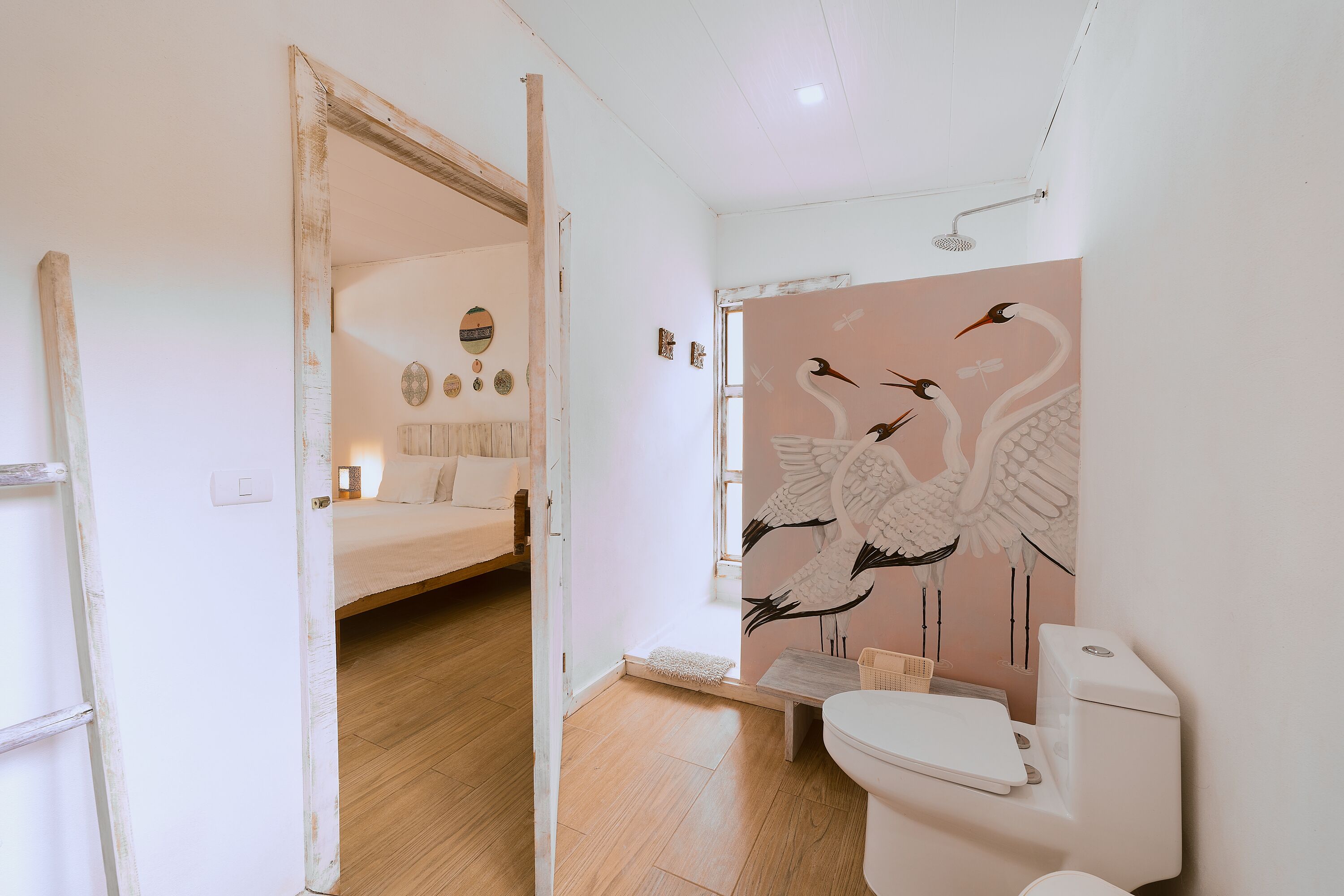 A bathroom with a toilet, shower, and a wall mural of swans.