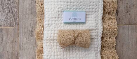 A white textured blanket with a Sonora soap label, placed on a woven mat.