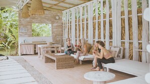 A rustic outdoor seating area with wicker furniture and a stone wall backdrop. - Sonora Caribbean Jungle Retreat (Cahuita)