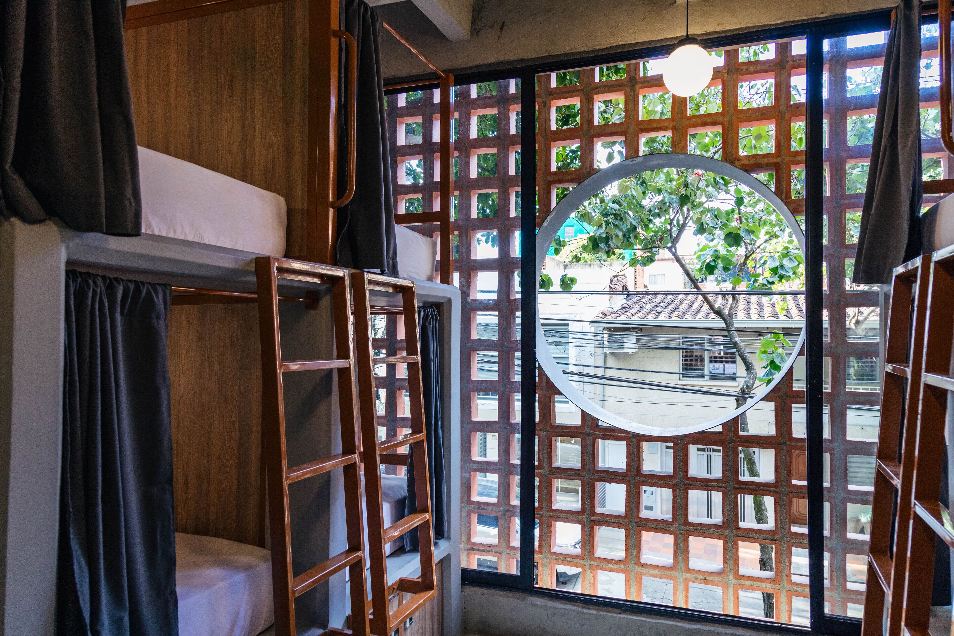 Un dormitorio con literas, una ventana con celosía de madera y vistas a un edificio tradicional.
