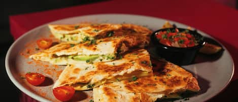 Un plato de quesadillas con tomates y una porción de salsa.