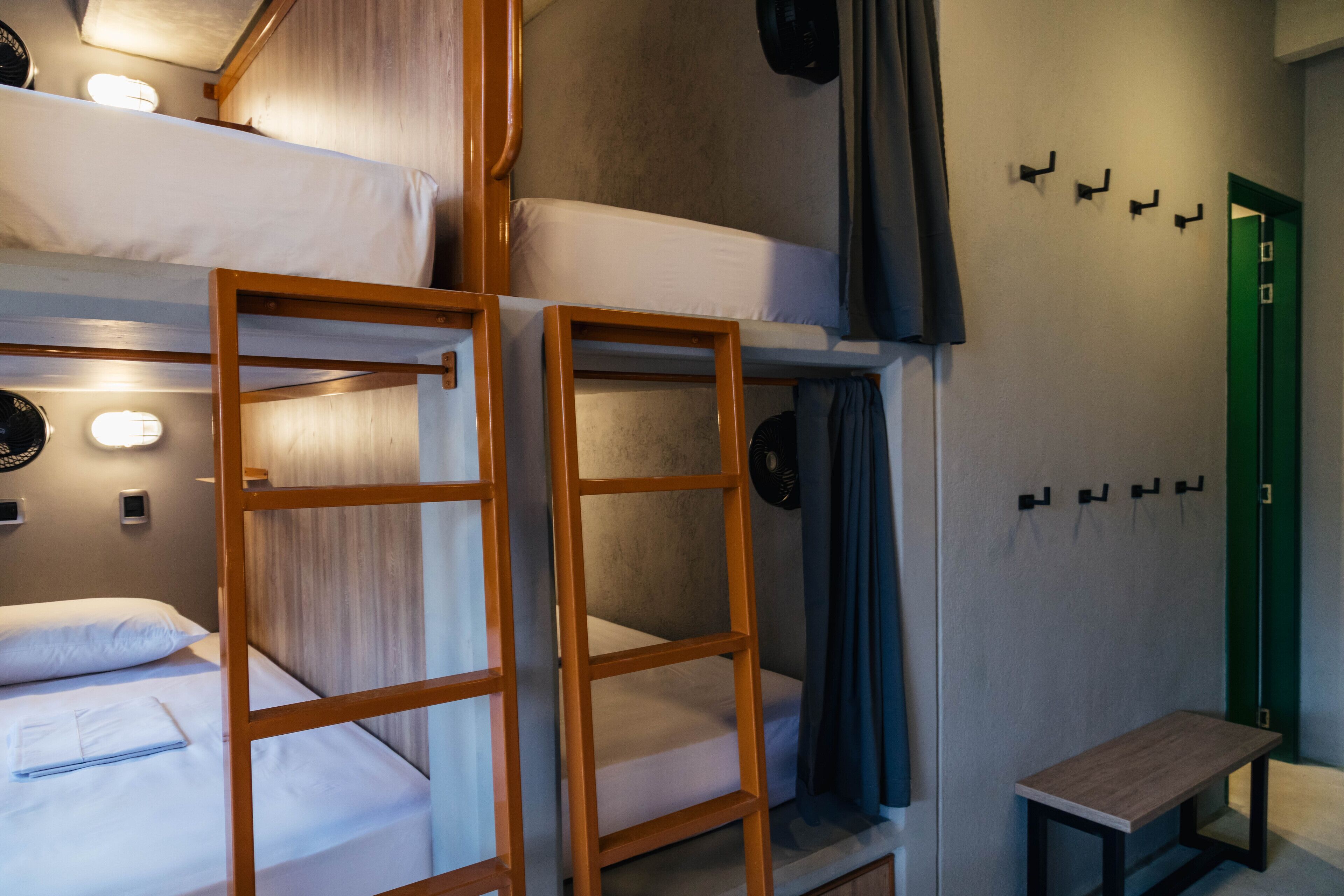 A bunk bed room with a wooden ladder, a small table, and a green door.