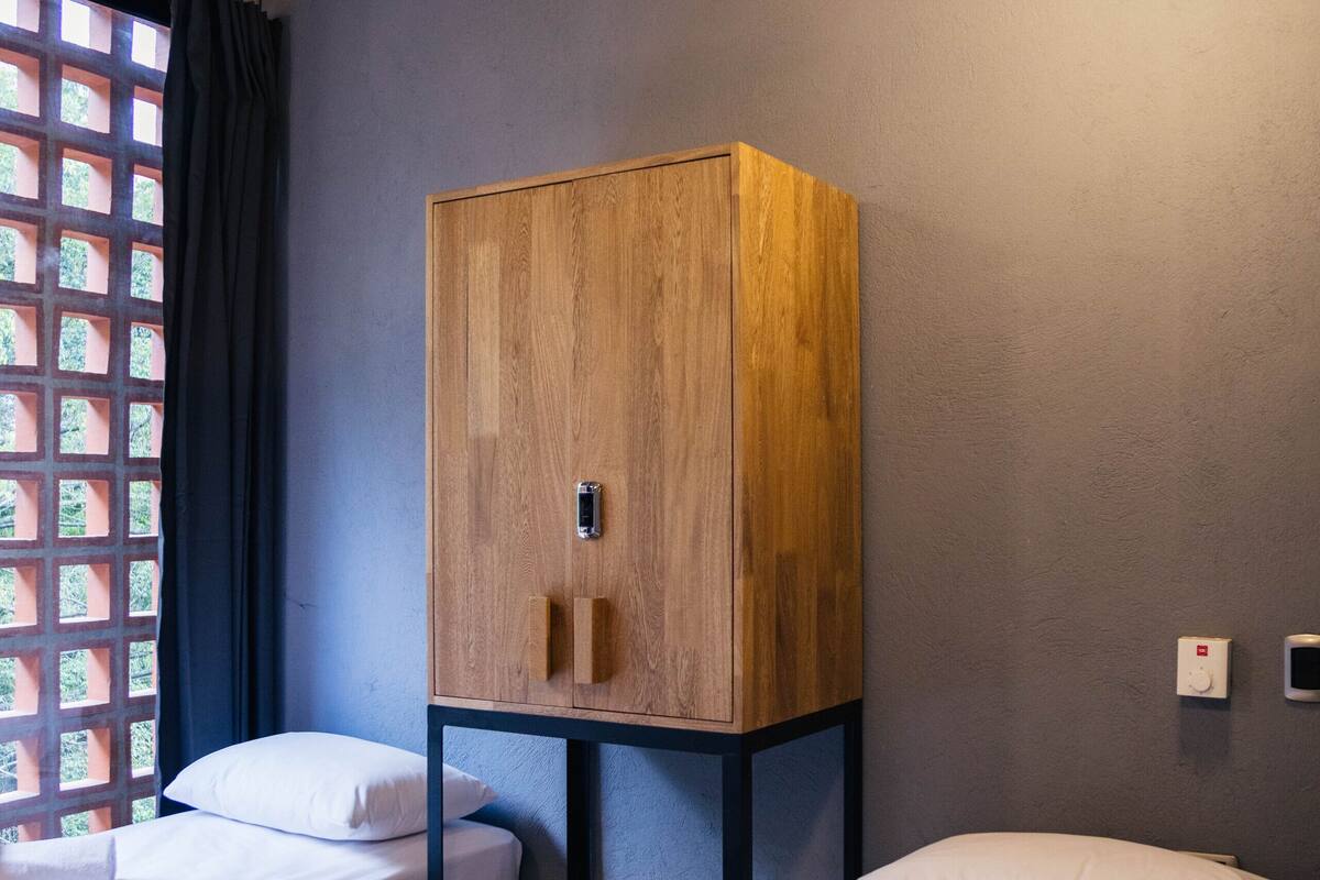 A room with two beds, a wooden wardrobe, and a ceiling fan.