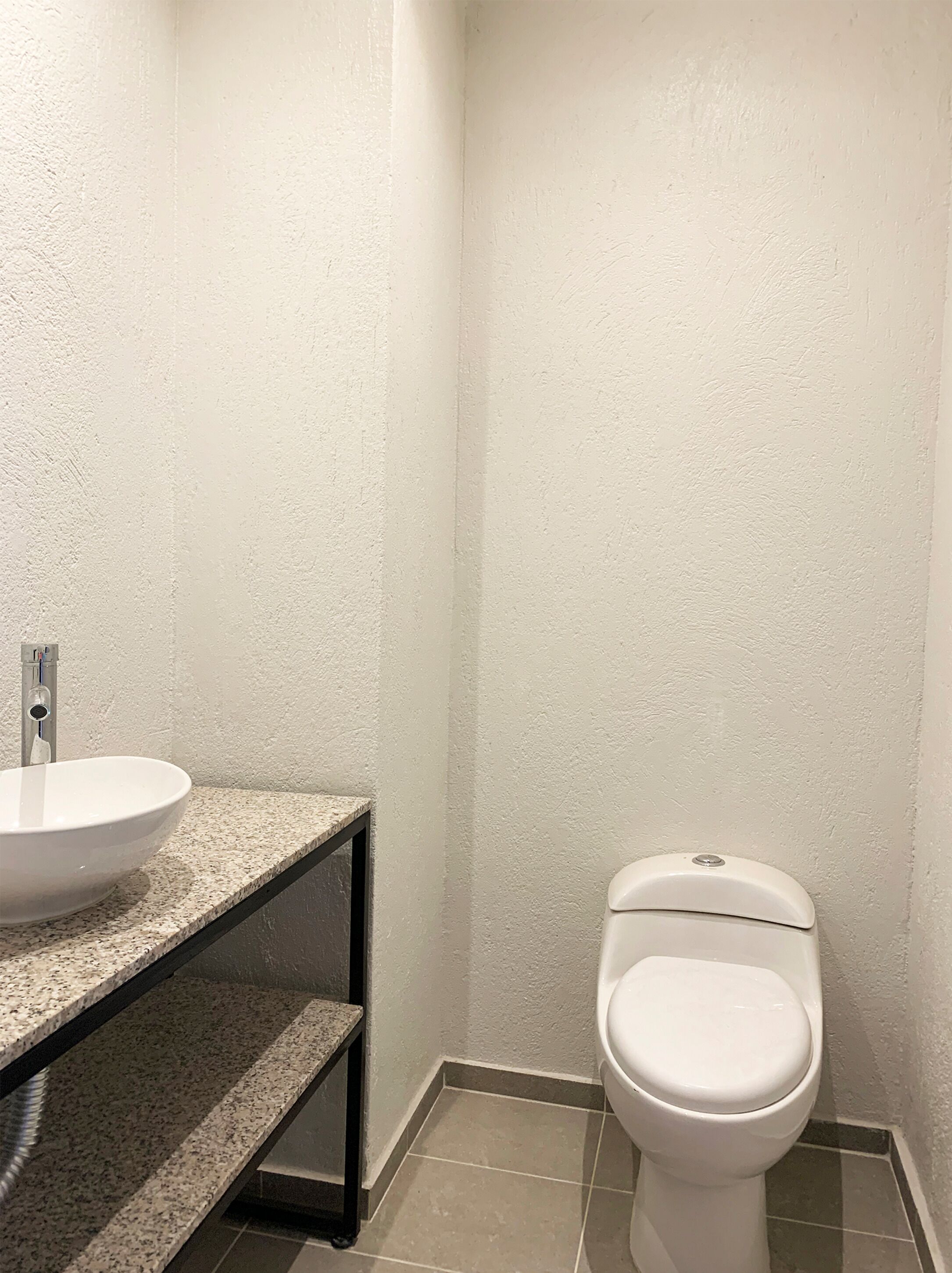 A bathroom with a white sink, a toilet, and a shelf.