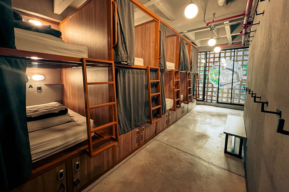 A compact, well-lit room with bunk beds, wooden cabinets, and a small table.