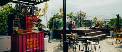 An outdoor patio with seating, a drink vending machine, and a stage for performances.