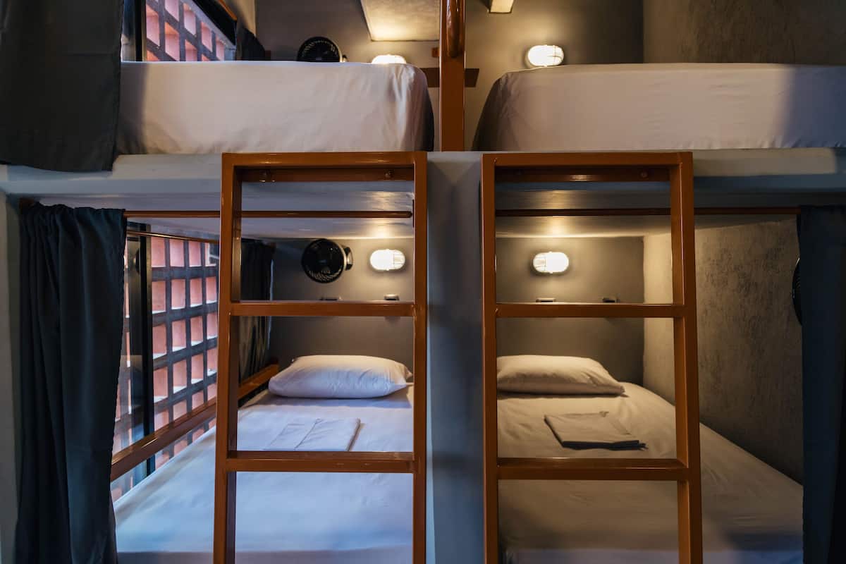 A room with two bunk beds, each with a headboard and a bedside lamp.