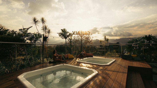 A rooftop with two hot tubs, surrounded by tropical plants and a clear sky. - Viajero Hostel Medellin (Medellín)