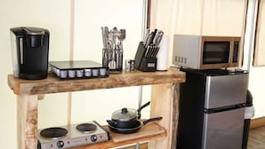 A compact kitchenette with a coffee maker, utensils, a microwave, a stove, and a refrigerator.