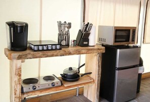 A compact kitchenette with a coffee maker, utensils, a microwave, a stove, and a refrigerator.