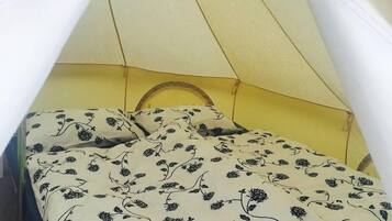 Ein Bett mit Baldachin, eine blumige Bettdecke und eine gelbe Wand.