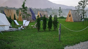 Een camping met meerdere houten huisjes, een tent en een grindpad.