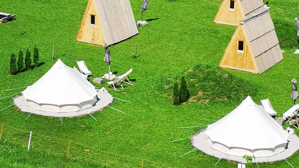 Een camping met meerdere tenten en een houten constructie.
