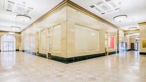 A spacious lobby with a checkered floor, large windows, and a high ceiling with skylights.