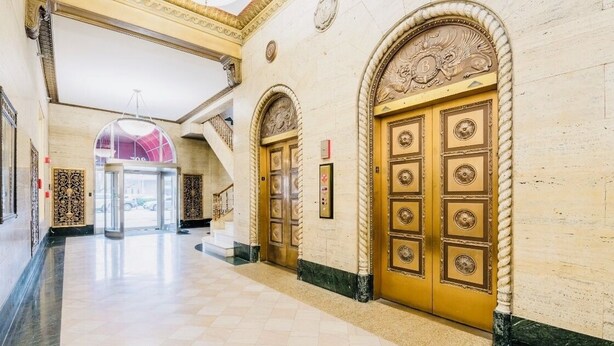 A grand hallway with ornate golden doors and a marble floor.