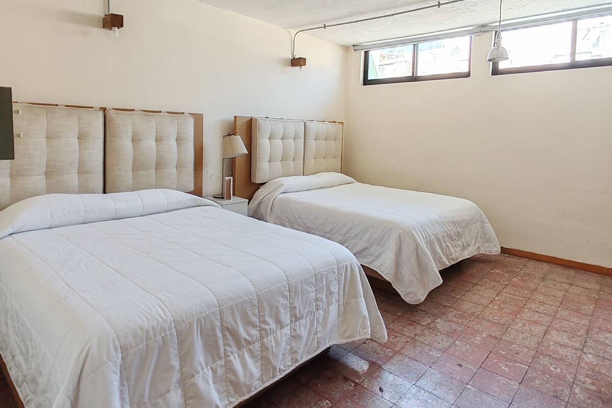 Una habitación con dos camas, una ventana y una lámpara en el techo.