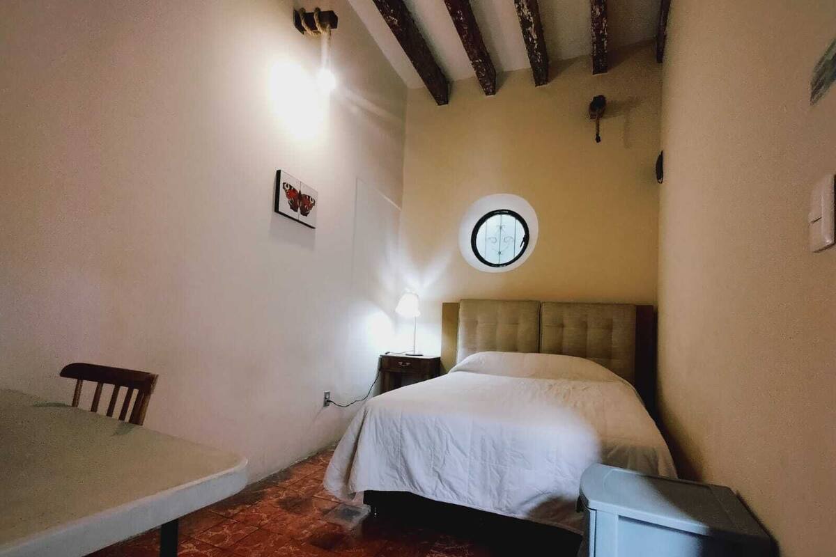 Una habitación pequeña y acogedora con una cama, una mesa y una silla.