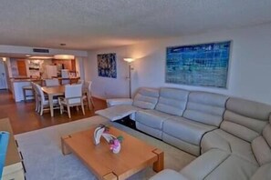 Relax in this stylish living room with a sofa, coffee table, and dining area, featuring a beautiful abstract painting.