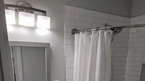 A bathroom with a sink, mirror, and shower curtain. - Ferrer's Villa Apt 2 close to beaches, parks, banks, market and parks. (Romblon Odiongan)