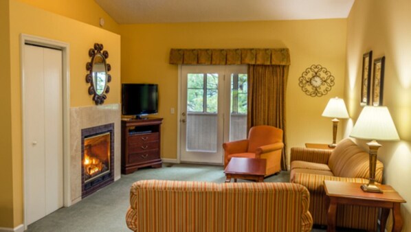 Una sala de estar con chimenea, televisor, sofá, sillón y lámpara.
