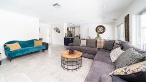 A spacious living area with a teal sofa, a grey sectional, and a round coffee table. - Luxury Water Front Villa! (Pompano Beach)